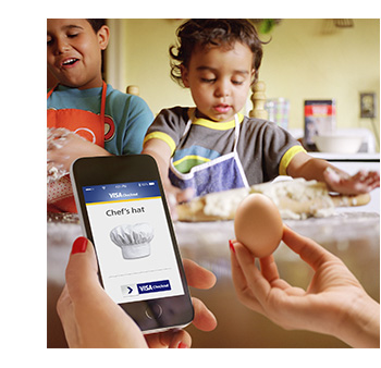 Picure of two young children helping to bake. Hands in foreground holding mobile phone and egg.